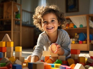 Niño pequeño sentado en el piso, feliz, jugando con bloques de madera. Concepto de desarrollo cognitivo infantil.