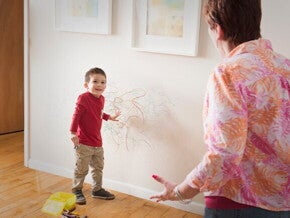 Cómo comportamientos desafiantes Niño con dibujos de crayón por la pared y un adulto reaccionando
