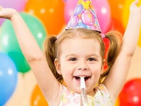 Niña pequeña feliz en un cumpleaños infantil con globos de colores.
