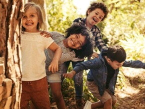 Hijo(a)s seguros y confiados Niños jugando bajo los árboles en un día soleado.
