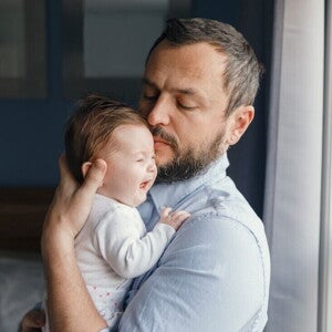 Papá sosteniendo a bebé llorando para ayudarle a eructar