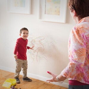 Cómo comportamientos desafiantes Niño con dibujos de crayón por la pared y un adulto reaccionando