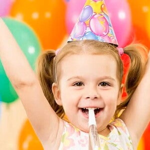 Niña pequeña feliz en un cumpleaños infantil con globos de colores.