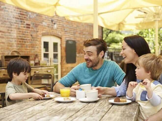 Estrategias efectivas para fomentar la autoestima de tus hijos Una familia y dos niños felices sentados en la mesa