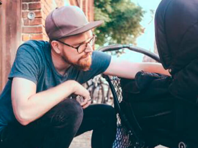 Conoce los consejos para comprar el coche para niños. Mamá y papá mirando a su niño en la carriola.