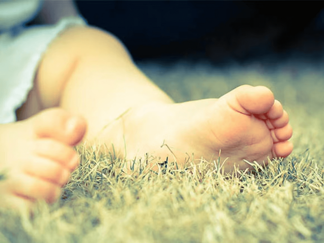Cómo identificar el pie plano en niños Pies de niño pequeño descalzo sobre césped seco al aire libre.