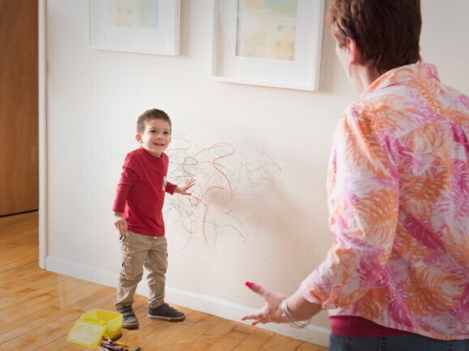 Cómo comportamientos desafiantes Niño con dibujos de crayón por la pared y un adulto reaccionando