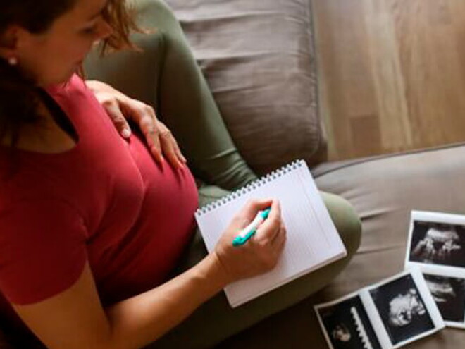 Tener un embarazo múltiple es muy común. Mamá con un cuaderno mirando la ecografía de su embarazo múltiple.