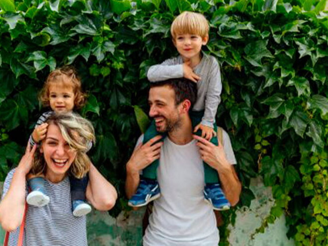 Estilos de crianza para educar a mi hijo. Los padres riendo con los hijos alzados.