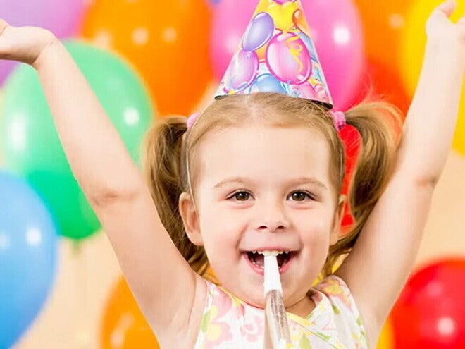 Niña pequeña feliz en una fiesta infantil con globos de colores