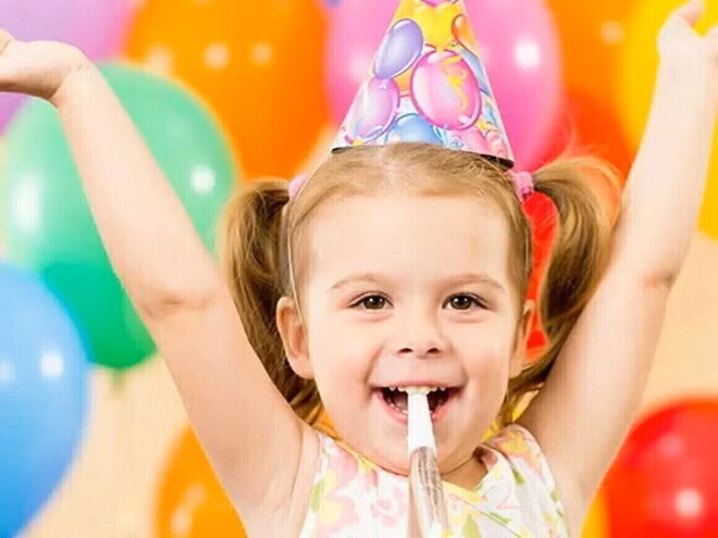Niña pequeña feliz en un cumpleaños infantil con globos de colores.