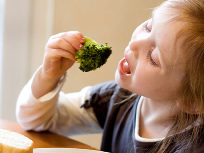 Conoce por qué son tan importantes los probióticos saludables en los niños. Una niña alimentándose con un brócoli.
