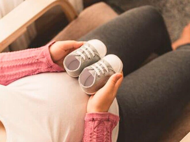 Conoce qué es el niño arcoíris. Mamá embarazada de un niño arcoíris cogiendo unos zapatitos.