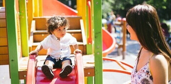 Actividades para fortalecer la motricidad gruesa Niño pequeño en el parque bajando de un tobogán para el desarrollo motor grueso.