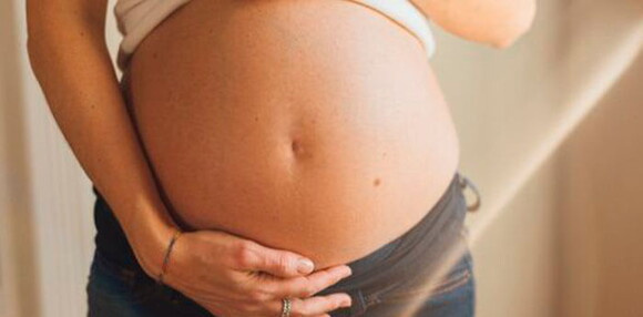 Conoce cuáles son las causas de la eclampsia. Mamá tocando el vientre.