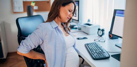 Identifica cuál es la diferencia entre preeclampsia y eclampsia. Mujer embarazada sentada sintiendo molestias.