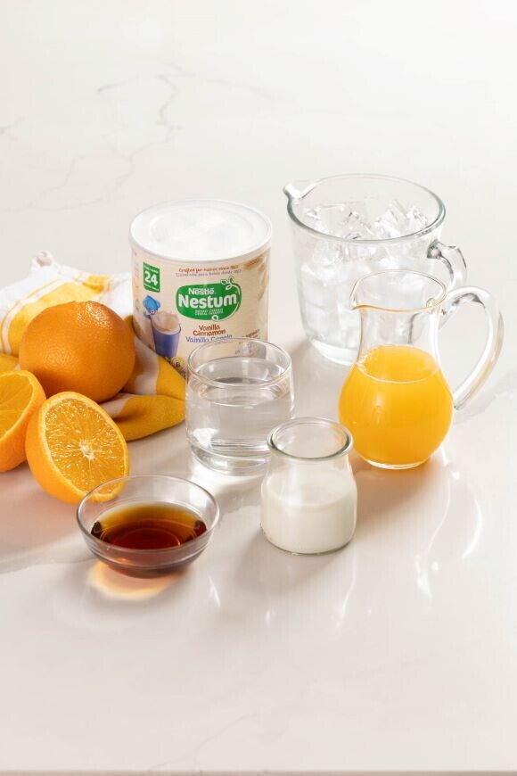 cereal nestum, naranjas, vasos y jarras encima de una mesa blanca