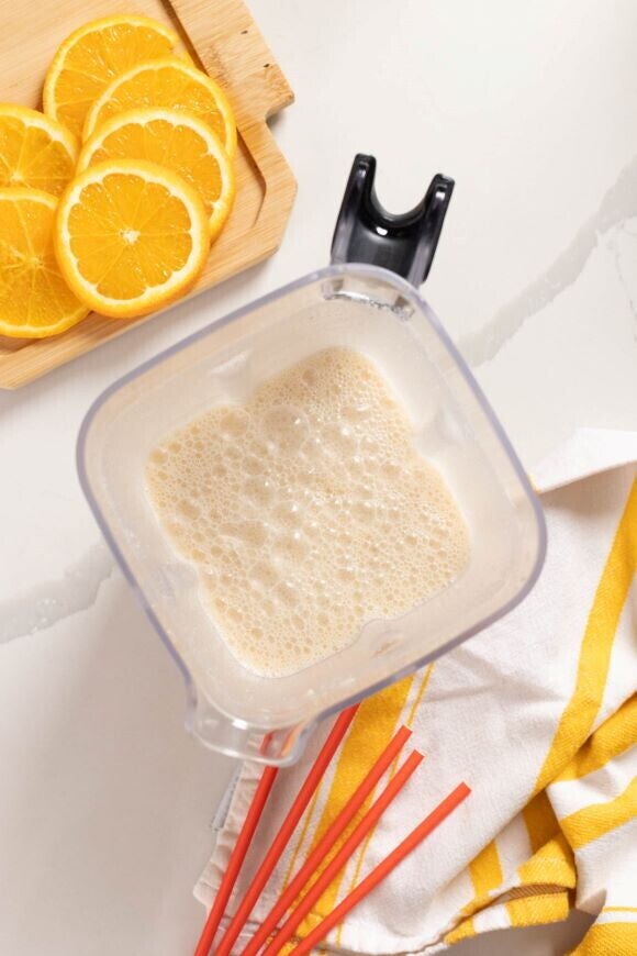 batido de nestum encima de la mesa con un plato con naranjas cortadas