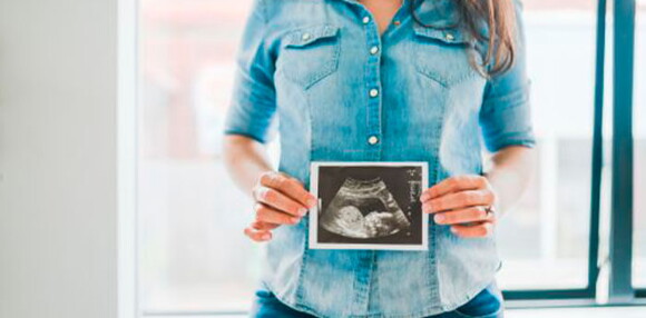 Conoce todos los cuidados en este nuevo embarazo. Mamá mostrando la ecografía de su niño arcoíris en camino.